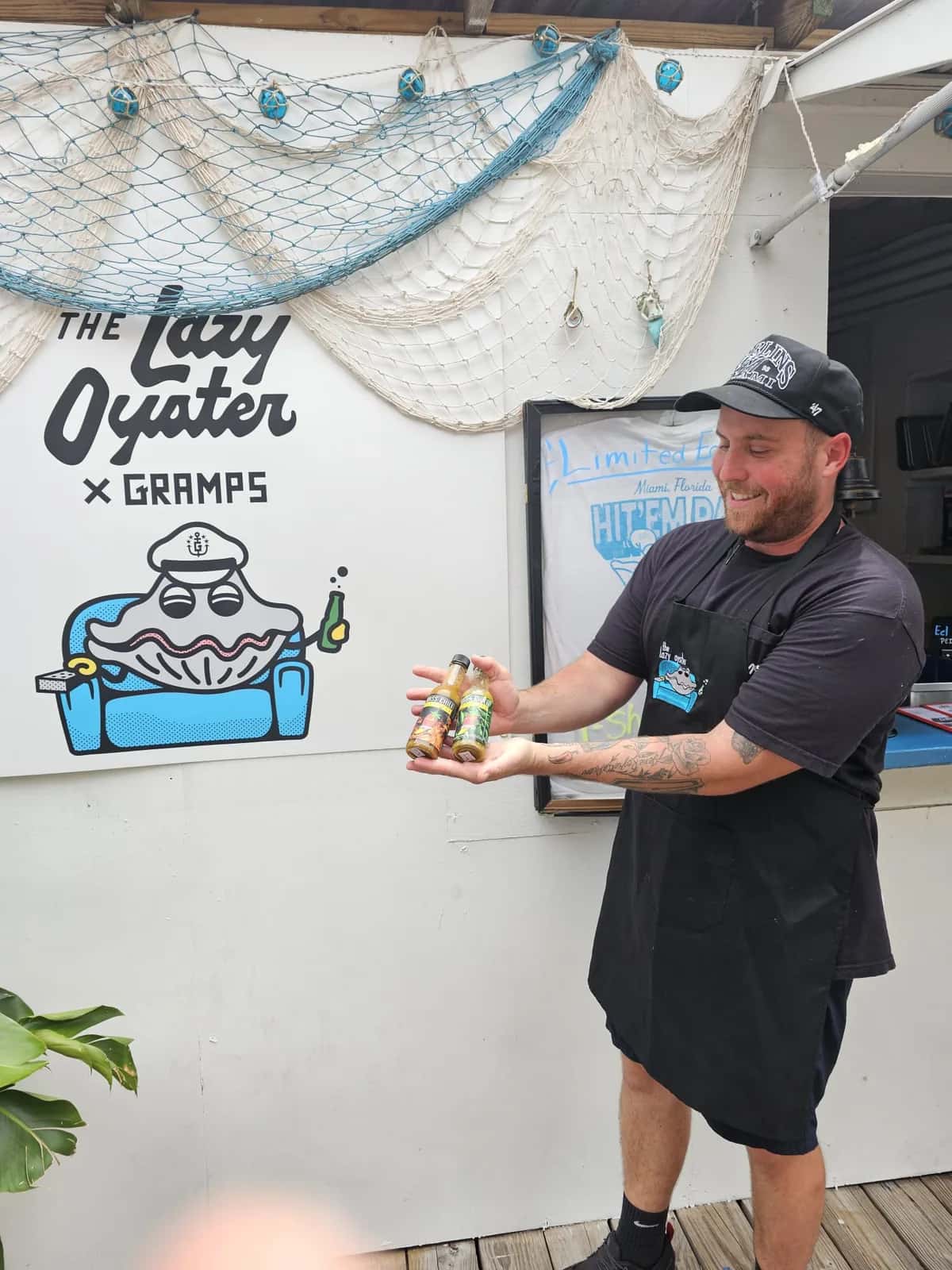 A restaurant partner holding Miss Chili hot sauce bottles at The Lazy Oyster in Miami