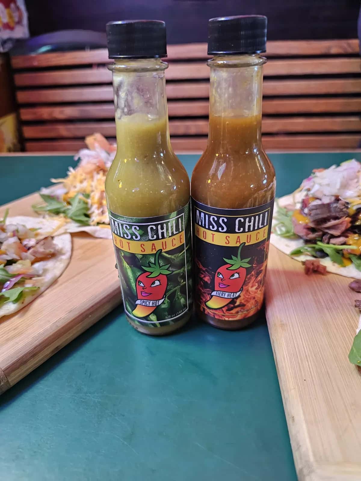 Spicy Hot and Fiery Heat bottles on a restaurant table beside a plate of tacos